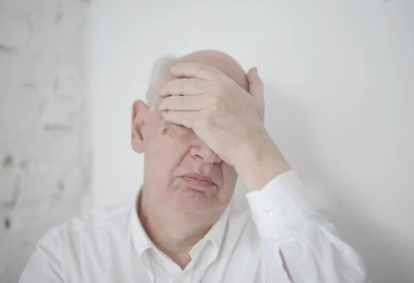 homem idoso segurando a cabeça com uma mão