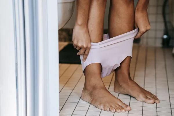mulher sentada no vaso levantando a calcinha