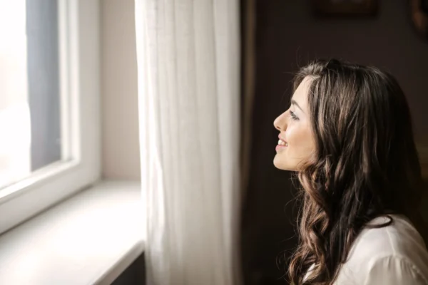 mulher sorrindo e olhando para janela
